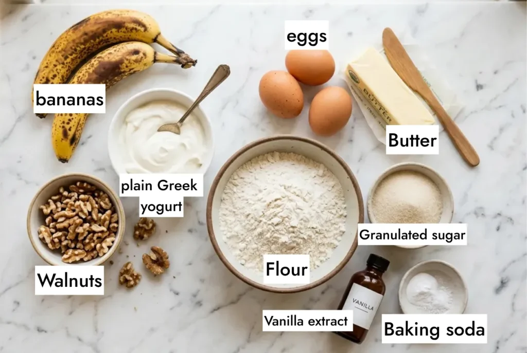 all ingredients banana bread recipe flatlay on white marble ripe bananas walnuts sour cream eggs butter flour