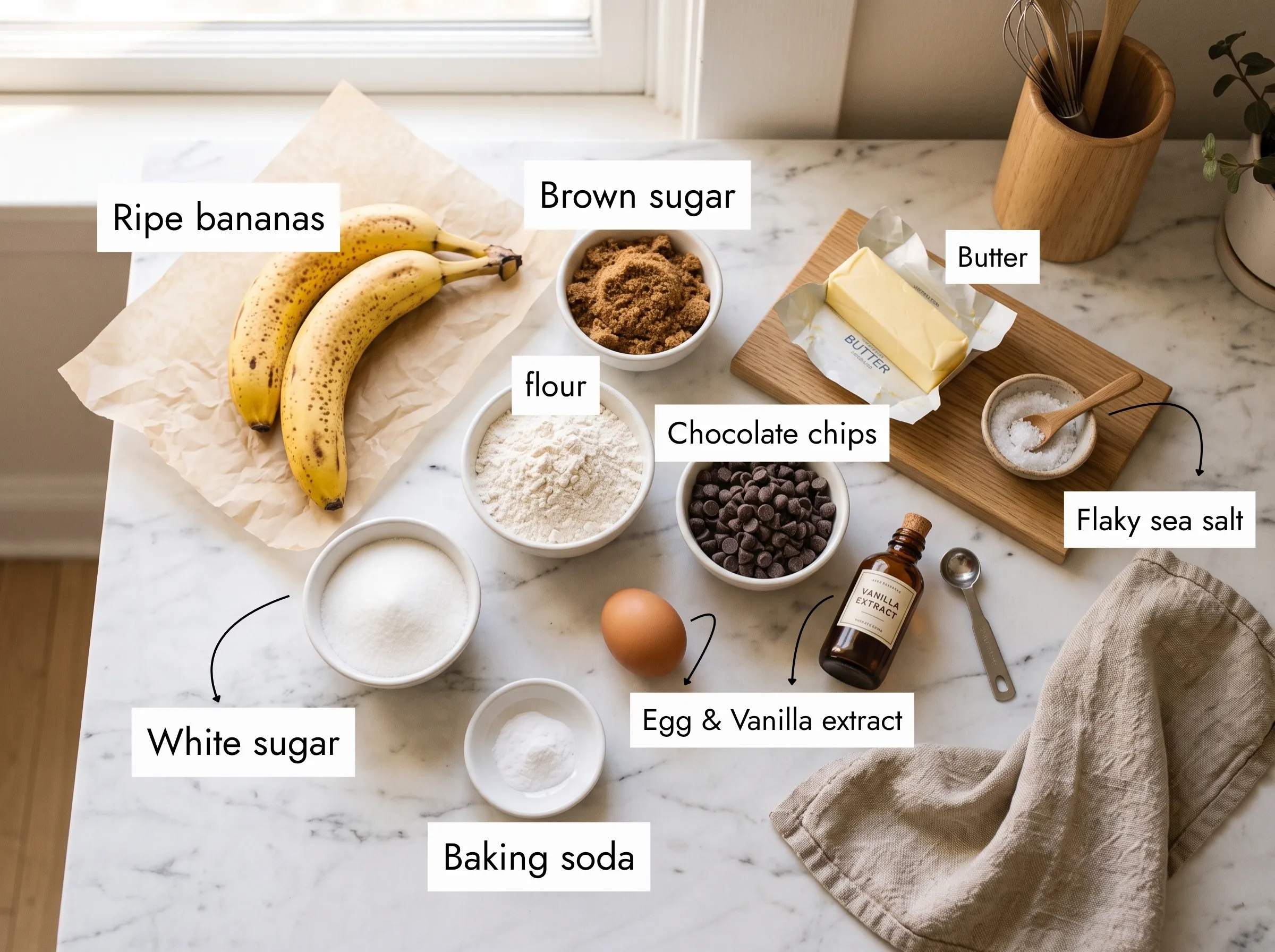 banana bread chocolate chip cookie ingredients flatlay on white marble — ripe bananas, dark chocolate chips, brown sugar