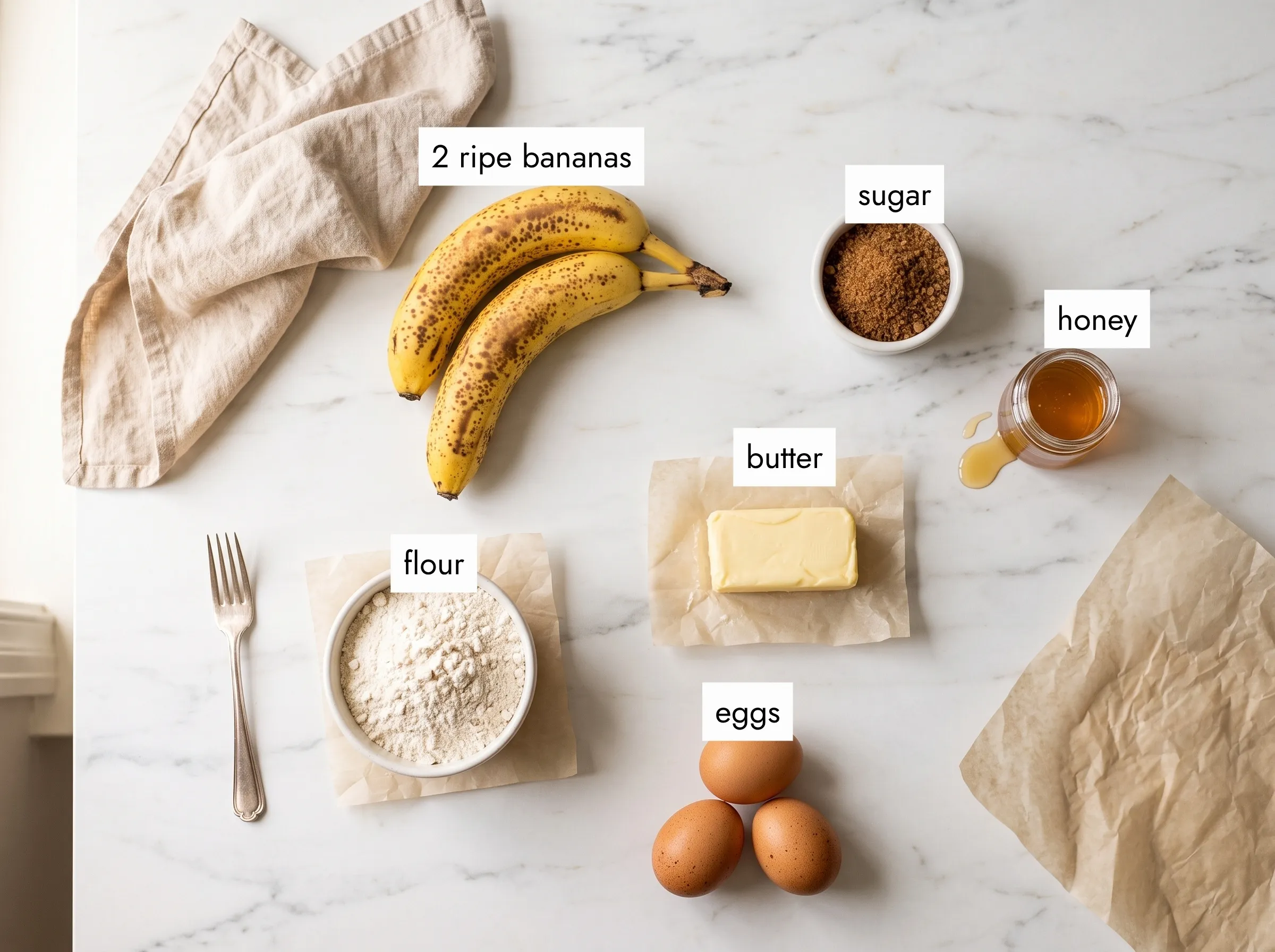 Overhead flat lay of banana cupcake recipe ingredients — ripe bananas, flour, eggs, butter, brown sugar and honey on white marble