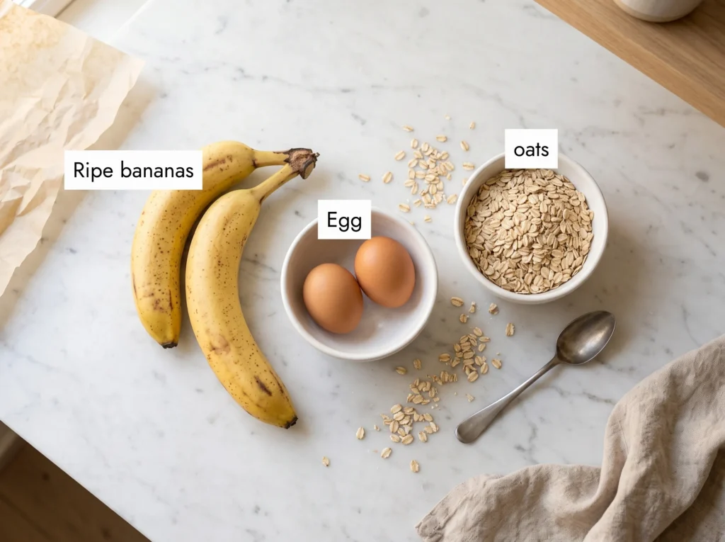 Three ingredients for banana oat pancakes — two ripe bananas, two eggs and rolled oats on white marble