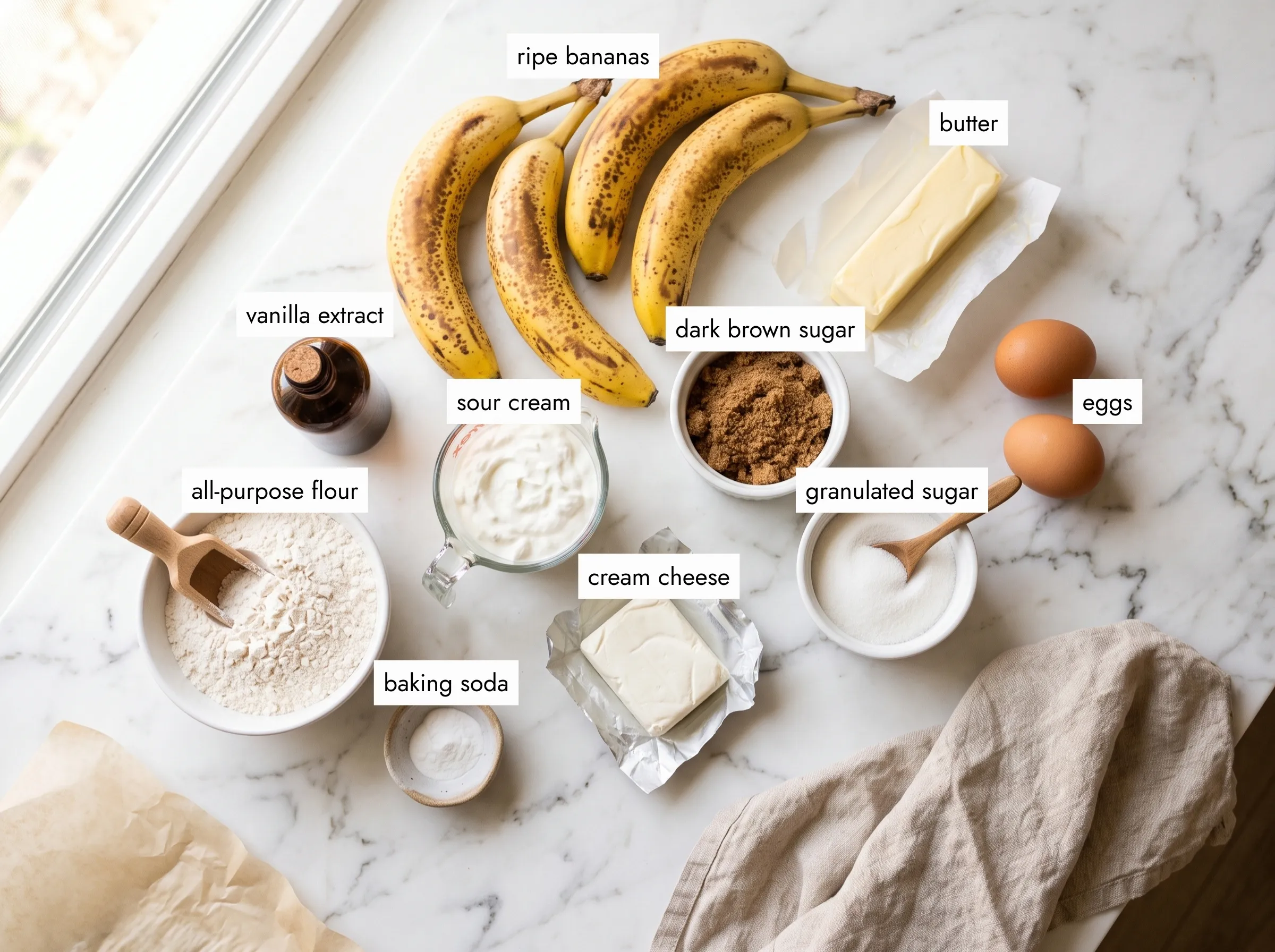 banana bundt cake ingredients overhead view with ripe bananas sour cream cream cheese and brown sugar on white marble