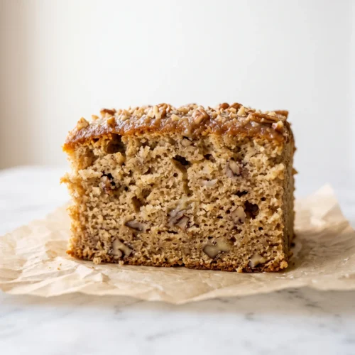 close up of moist banana nut cake crumb with golden pecan pieces and glossy brown butter glaze